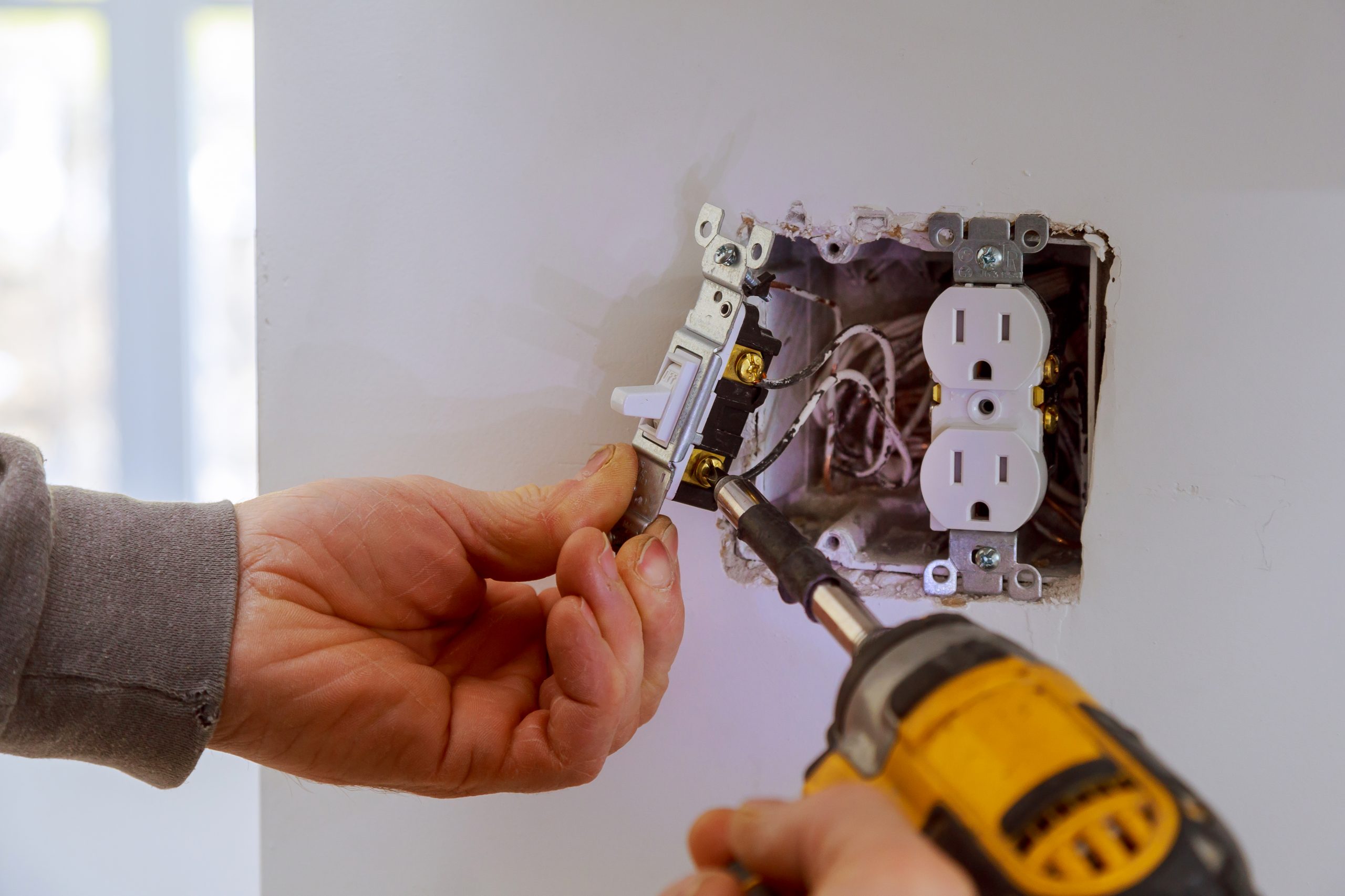 an electrician installing a power switch to the electrical junction box
